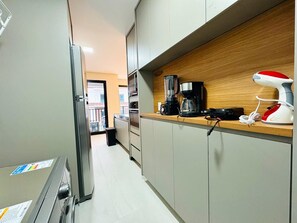 A modern kitchen with a built-in coffee maker, a toaster, and a kettle on the countertop. - Apartment 3S across from the Shopping Center next to Vaca Brava Park (Goiânia)