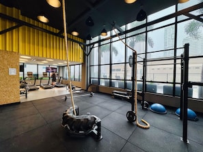 A gym with treadmills, weightlifting equipment, and large windows.