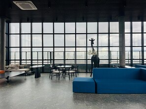 A modern lounge with large windows, a giraffe sculpture, and seating arrangements.