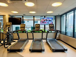 A gym with treadmills, stationary bikes, and a TV displaying news. - Apartment 3S across from the Shopping Center next to Vaca Brava Park (Goiânia)