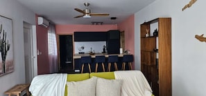 A bedroom with a bed, a desk, and a chair. There is a ceiling fan and a window with curtains. - Les Quatre Îlots – 2-Bedroom Apartment in Friar's Bay   (friar's bay)