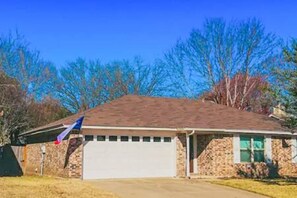 A single-story house with a garage, a brick exterior, and a clear blue sky. - Backyard + Office + Clean + Comfy Beds (Fort Worth)