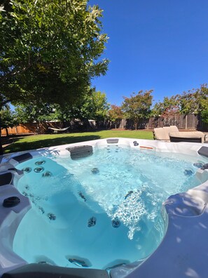 A hot tub with a clear blue pool, surrounded by a wooden fence and trees. - Wine Country Retreat 5BR w/ Hot Tub (American Canyon)