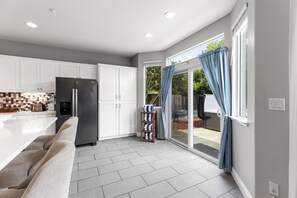 A modern kitchen with white cabinets, a stainless steel refrigerator, and a built-in oven. - Wine Country Retreat 5BR w/ Hot Tub (American Canyon)