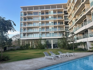 A multi-story hotel with a swimming pool, outdoor seating, and a well-maintained lawn. - BEAUTIFUL BEACHFRONT APARTMENT (Cruz de Huanacaxtle)