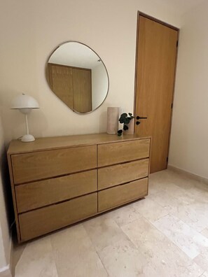 A wooden dresser with drawers, a round mirror, a white lamp, and a potted plant. - BEAUTIFUL BEACHFRONT APARTMENT (Cruz de Huanacaxtle)