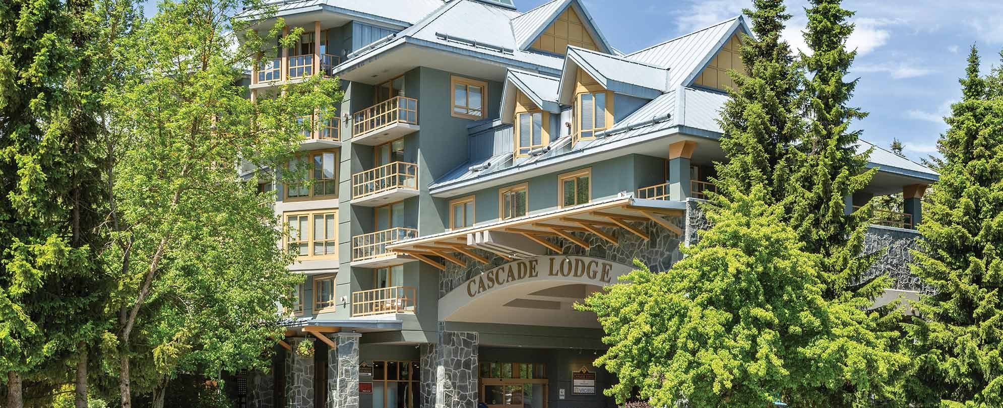 A multi-story hotel with balconies, stone pillars, and a sign reading "Cascade Lodge".