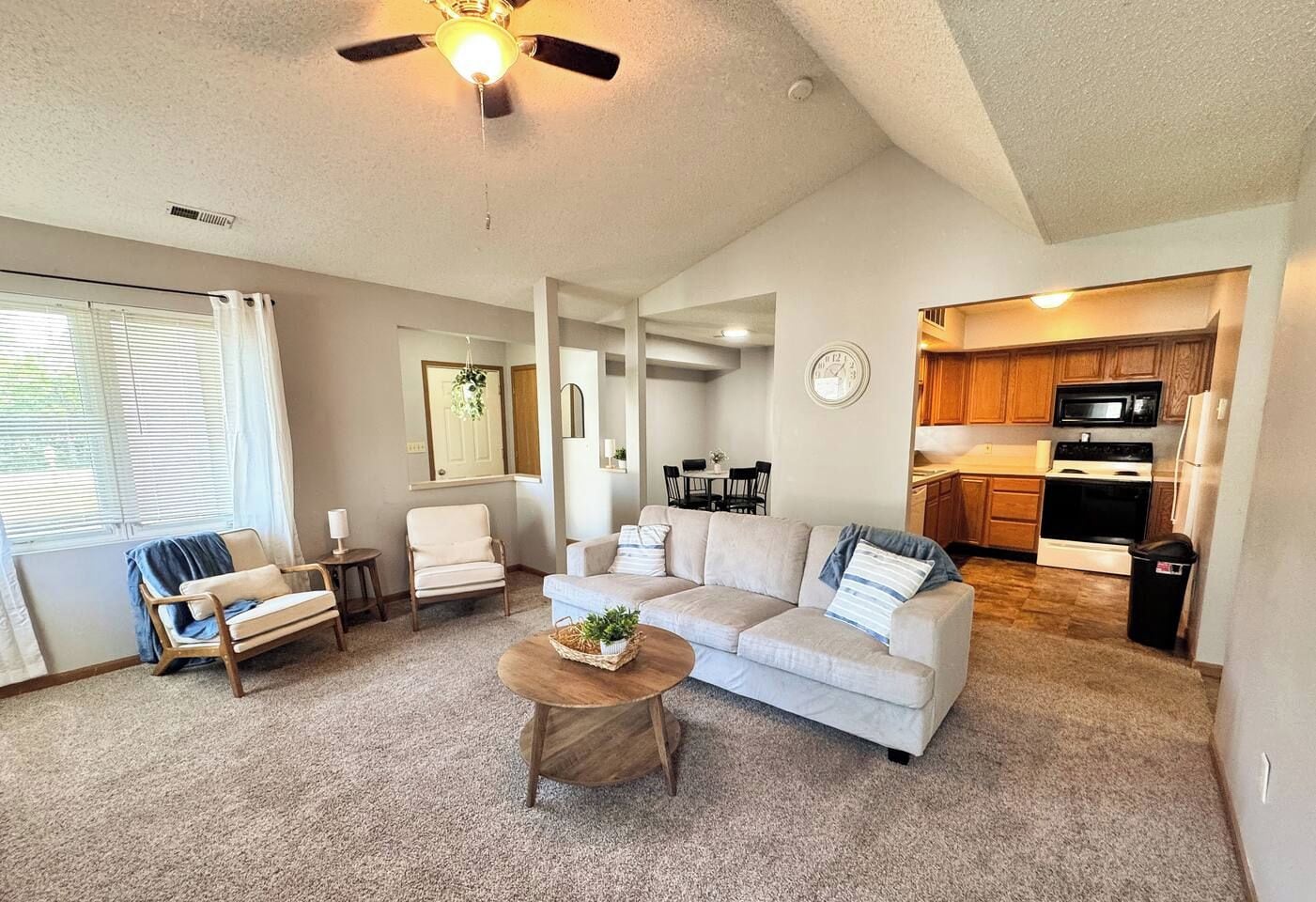 A living room with a sofa, chairs, a coffee table, and a ceiling fan.