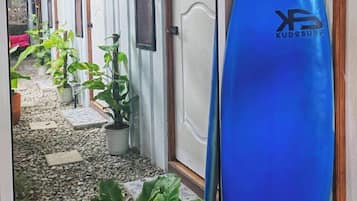 Een gang met deuren naar kamers, een blauw surfplank en potplanten.