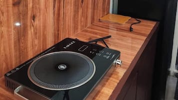 A wooden counter with a black electronic device, possibly a speaker or audio equipment, and a white lamp on a black table.