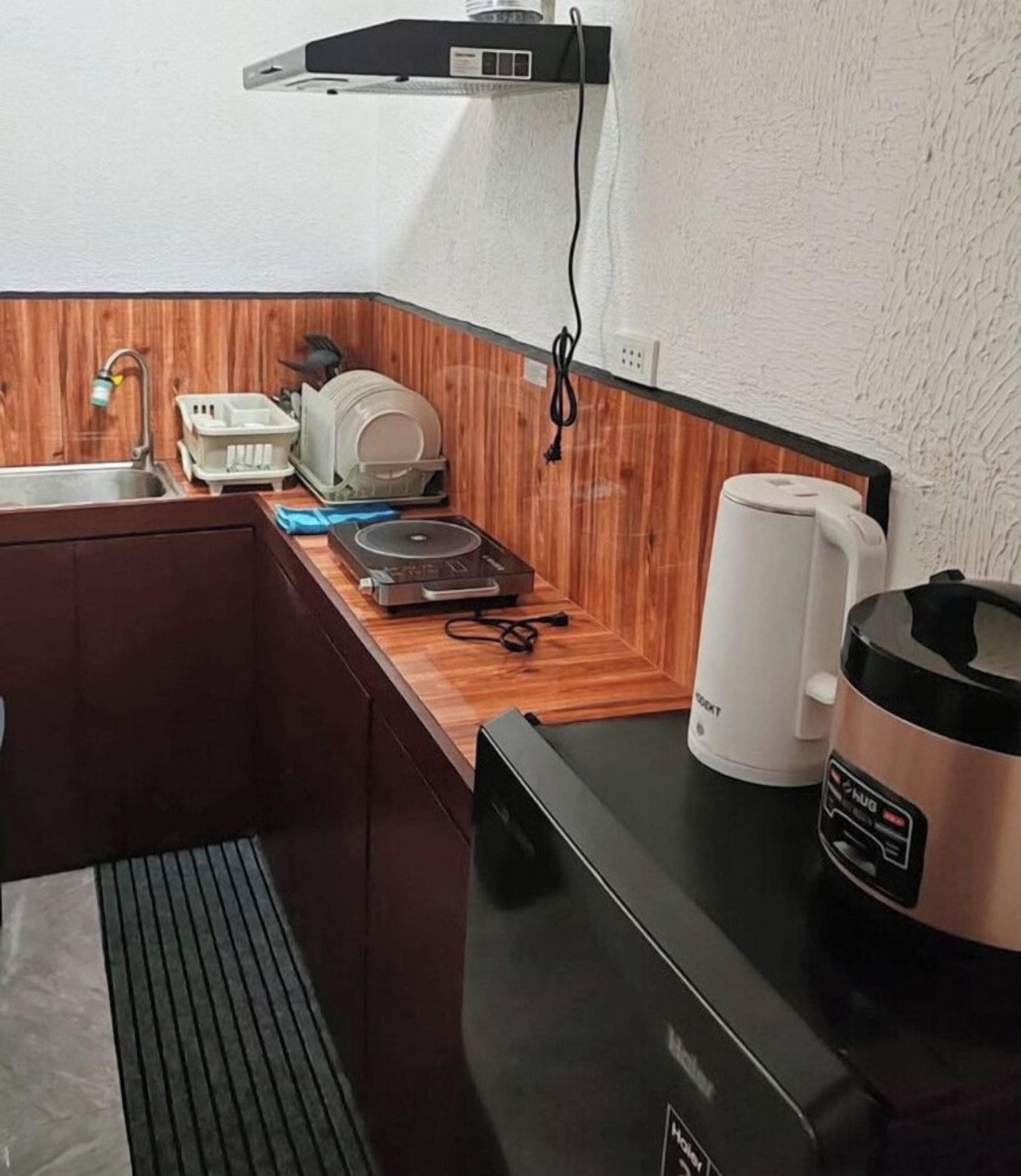 Een compact keukenhoekje met een spoelbak, een koffiezetapparaat, een rijstkoker en een klein aanrecht.