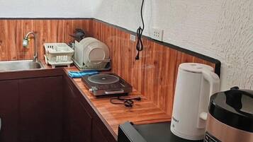 Een compact keukenhoekje met een spoelbak, een koffiezetapparaat, een rijstkoker en een klein aanrecht.