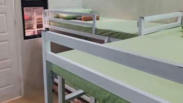 Een kamer met stapelbedden, een deur en een raam met uitzicht.