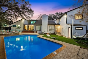 Una propiedad residencial con piscina, mobiliario exterior y césped bien cuidado.
