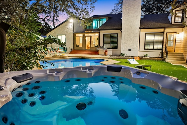 A residential property with a swimming pool, hot tub, and a well-maintained lawn.