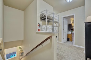 A multi-level interior with a staircase, a white door leading to another room, and a black cabinet. - Cobblestone Landing! 3BR Mid-Term Stay Near UCCS (Colorado Springs)