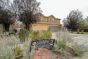 A residential house with a garage, surrounded by a garden with various plants and a bench. - Cobblestone Landing! 3BR Mid-Term Stay Near UCCS (Colorado Springs)