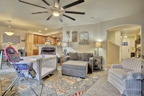 A spacious living room with a ceiling fan, a baby rocker, a grey sofa, and a patterned rug. - Cobblestone Landing! 3BR Mid-Term Stay Near UCCS (Colorado Springs)