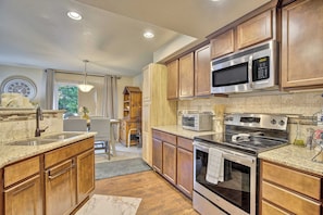 A kitchen with wooden cabinets, a stainless steel microwave, a stove, and a sink. - Cobblestone Landing! 3BR Mid-Term Stay Near UCCS (Colorado Springs)