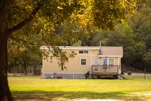 Une maison mobile de plain-pied avec une cour clôturée, une terrasse et un petit porche.