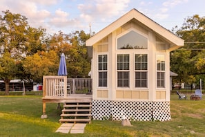 A small wooden cabin with a porch, a deck, and a fenced area. - Pets Welcome! Tiny House + Guadalupe River Access (New Braunfels)