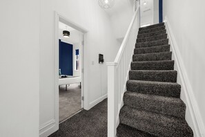 Un escalier dont les marches sont recouvertes de moquette, menant à un palier.