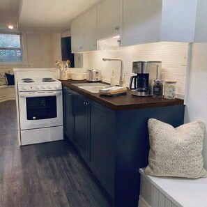 A modern kitchen with a stove, sink, and coffee maker. - Charming & Furnished Roncesvalles Suite. Pet Friendly! (Toronto)