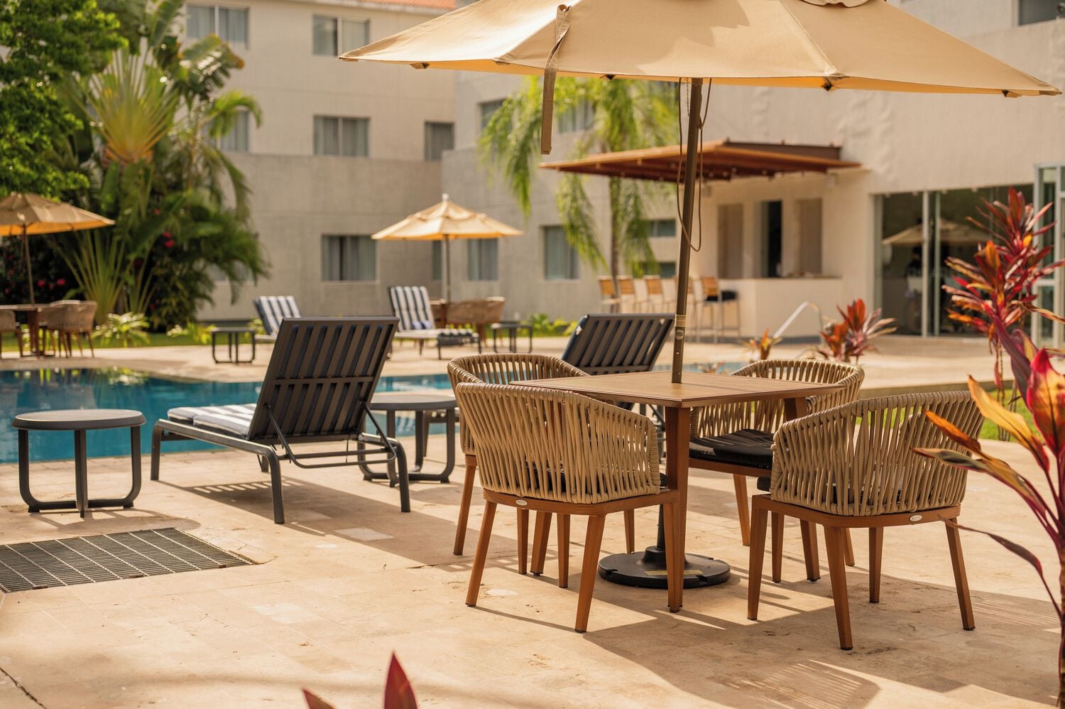 Un espace aménagé au bord de la piscine, avec des chaises longues, une table et des parasols.