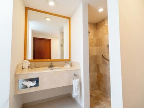 Baño con lavamanos, espejo, toallero y zona de ducha.
