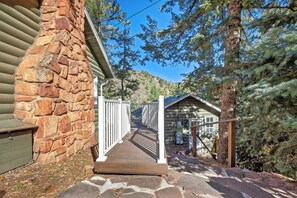 Un mur extérieur en pierre, une terrasse en bois et un portail en métal menant à un chalet.