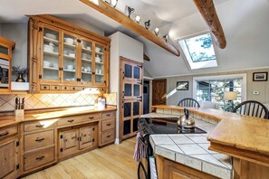 Une cuisine avec des meubles en bois, un grand îlot central et une lucarne.