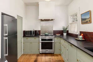 A compact kitchen with a refrigerator, microwave, stove, and oven. - Charming historic bungalow in prime location (Tucson)