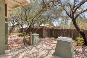An outdoor patio area with a wooden fence, a concrete table, and a bench. - Charming historic bungalow in prime location (Tucson)