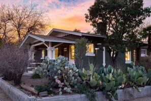 A house with a front porch, a cactus garden, and a sunset sky. - Charming historic bungalow near University (Tucson)