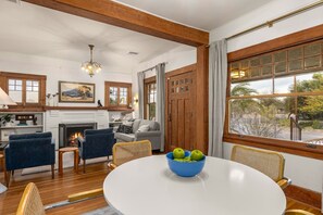 A dining area with a round table, chairs, a bowl of apples, and a fireplace. - Charming historic bungalow near University (Tucson)