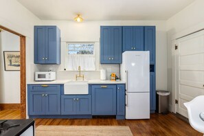 A compact kitchen with blue cabinets, a white refrigerator, and a microwave. - Charming historic bungalow near University (Tucson)