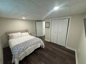 Une chambre à coucher avec un lit, une armoire, une table de chevet et une porte.