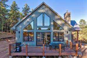A modern cabin with a large deck, multiple windows, and a stone chimney. - Conestoga Creek! NEW Secluded Cabin w/Deck & Views (Florissant)