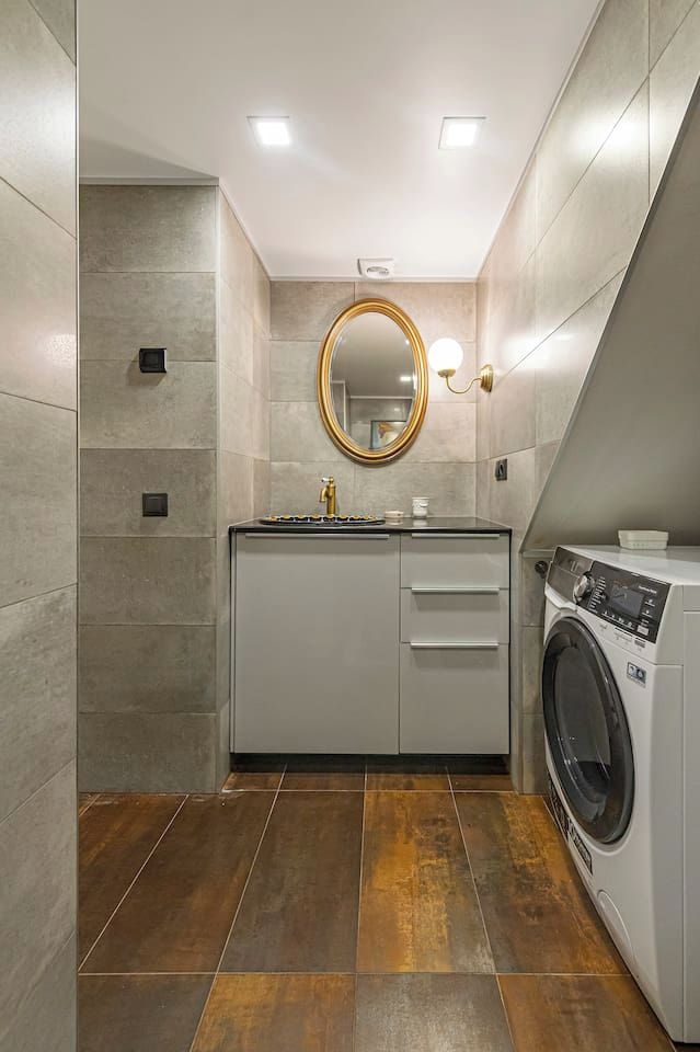 Une petite salle de bain équipée d’un lave-linge intégré, d’un lavabo avec un miroir et d’un porte-serviettes.