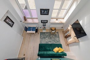 Un espace de vie compact comprenant un canapé vert, une table à manger et un petit coin cuisine.