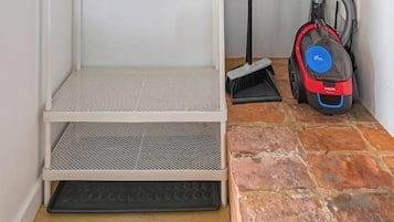 A room with a metal shelving unit, a vacuum cleaner, and a water heater.
