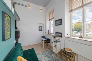 Un espace de vie compact comprenant un coin cuisine, un coin repas et une vue sur le paysage urbain grâce à de grandes fenêtres.