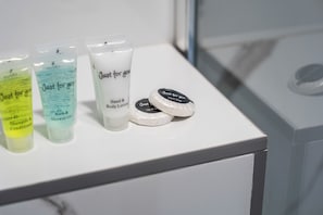 Ein weißes Regal mit verschiedenen Pflegeprodukten, darunter Hand- und Körperlotion, Duschgel und Shampoo-Conditioner.