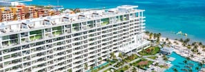 A high-rise hotel with multiple balconies, a pool area, and a view of the ocean. - Luxury Junior Suite Cancun – Oceanfront Resort Getaway (Cancún)