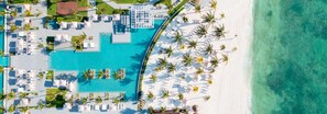 An aerial view of a resort with a swimming pool, sun loungers, and palm trees. - Luxury Junior Suite Cancun – Oceanfront Resort Getaway (Cancún)