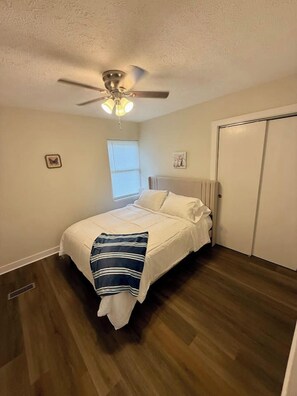 A bedroom with a bed, a ceiling fan, a window, and a door. - Nebraska City Nook - Oak (1310 1st Ave) (Nebraska City)