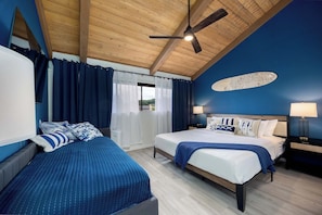 Ein Schlafzimmer mit einem großen Bett, einem Deckenventilator und Blick ins Freie.
