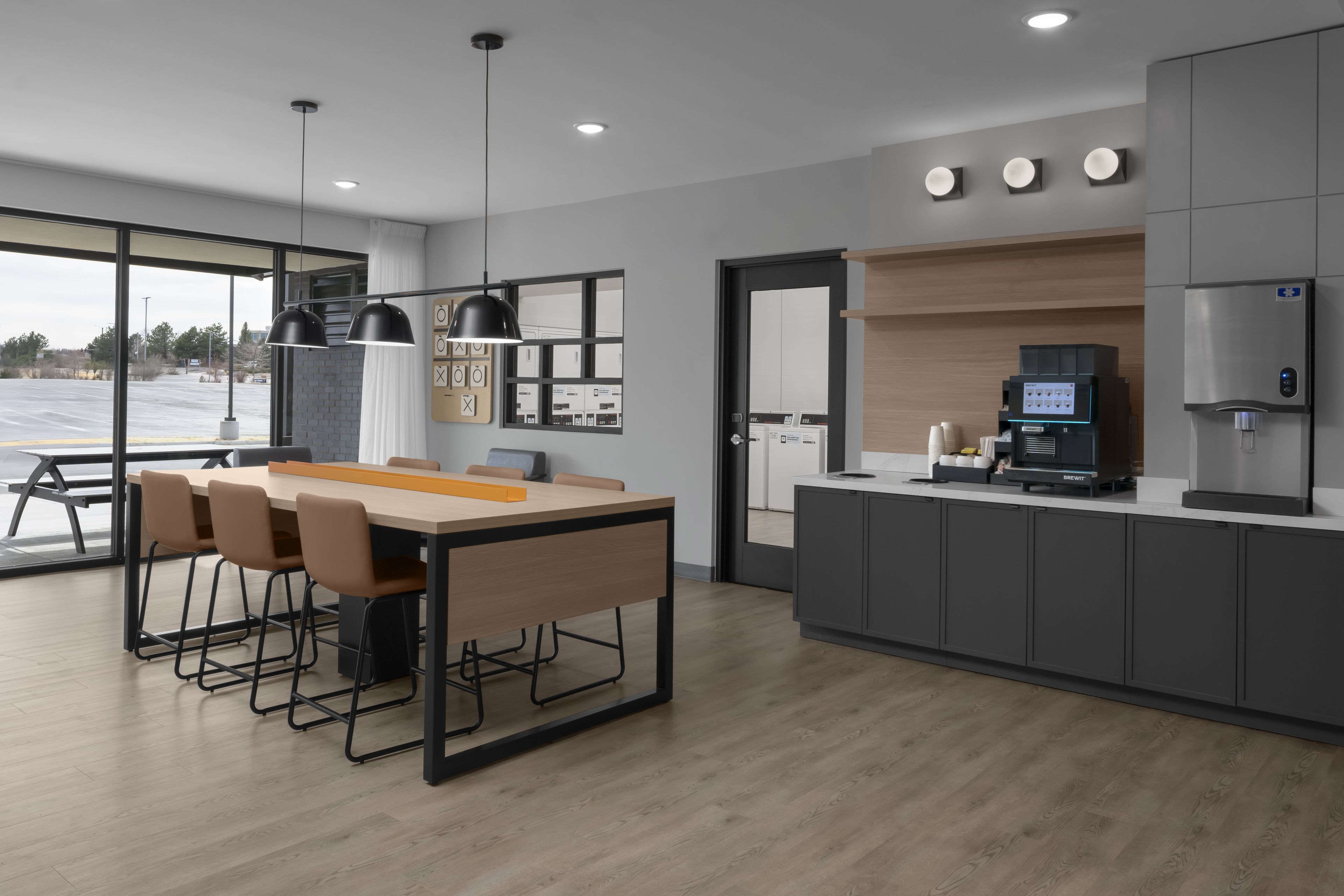 Una cocina moderna con una isla central, electrodomésticos integrados y un comedor con un ventanal amplio.