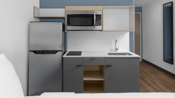 A compact kitchenette with a refrigerator, microwave, and sink.