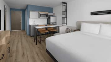 Ein Hotelzimmer mit einem Bett, einem Schreibtisch mit Stuhl, einer Mikrowelle und einem Kühlschrank.